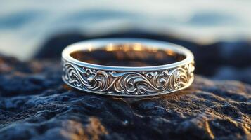 Intricate silver ring with floral motifs displayed on a textured stone surface photo