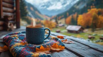 Warm tea in a glass mug resting on a cozy blanket by a log cabin in autumn woods photo