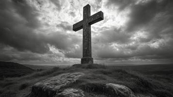 Celtic cross standing on a hill under dark stormy sky at dusk with dramatic clouds and moody atmosphere photo