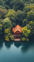 Modern cabin surrounded by lush greenery on a serene lake at dusk photo