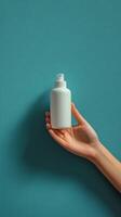 Hand holding a white pump bottle against a teal background photo
