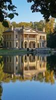 Majestic mansion reflected in serene waters surrounded by lush greenery in a tranquil setting photo