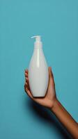 Hand holding a white pump bottle against a teal background photo