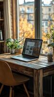 Cozy workspace with laptop by window surrounded by greenery on a sunny autumn morning photo
