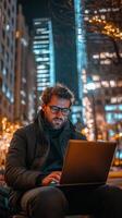Focused individual working on a laptop in a city cafe at night photo