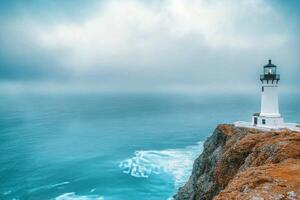 Lighthouse overlooking the ocean during clear skies in a coastal landscape photo