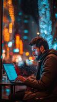 Focused individual working on a laptop in a city cafe at night photo