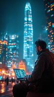 City dweller working on laptop at night in urban park with glowing skyscrapers photo