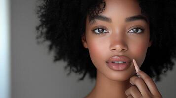 Young woman applies nude lipstick in a close-up shot with natural makeup photo