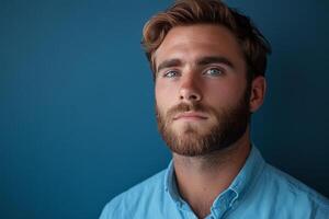 Handsome man with a beard and blue eyes posing in casual attire against a neutral background photo