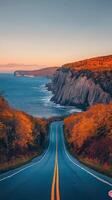 Scenic coastal road winding along the ocean during sunset near a peaceful seaside town photo