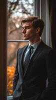 Business professional in suit gazing thoughtfully out of window during golden hour photo