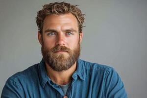 Handsome man with a beard and blue eyes posing in casual attire against a neutral background photo