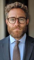 Professional man with glasses poses confidently in a formal suit against a dark background photo