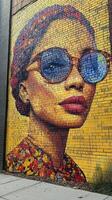 Colorful mural of a woman with sunglasses displayed on a brick wall in an urban setting photo