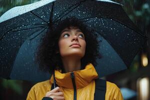 Woman enjoying autumn rain under a black umbrella in a park with vibrant yellow leaves photo