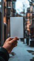 Hand holding a blank card in a bustling street adorned with soft, glowing lights photo