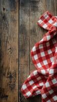Red and white checkered cloth on rustic wooden table with fresh herbs nearby photo