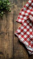Red and white checkered cloth on rustic wooden table with fresh herbs nearby photo