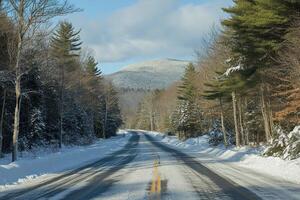 Winter road through a snowy landscape with mountains in the background under clear blue sky photo