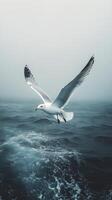 Seagull soaring above calm ocean waters on an overcast day photo