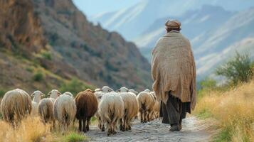 Shepherd guiding a flock of sheep through a mountainous landscape during daylight hours photo