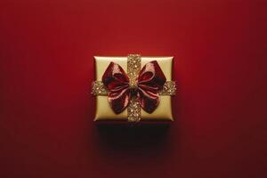 Shimmering gold gift box with red ribbon on vibrant red background ready for a special occasion photo