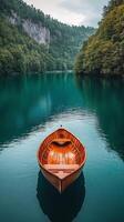 canoa descansando pacíficamente en el apuntalar de un tranquilo lago rodeado por lozano verde arboles foto
