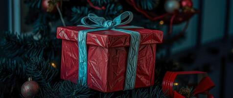 red gift box with teal ribbon on artificial tree photo