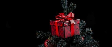 red gift box with ribbon on artificial tree branch photo