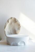 white pedestal with a textured circular form front it photo