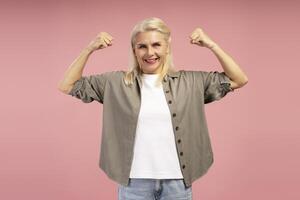 Strong confident woman flexing biceps on pink background photo