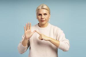 Serious woman showing small amount or tiny size with hand gesture on blue background photo