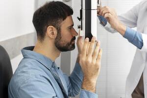 Optometrist examining patient's eyesight with slit lamp biomicroscope photo