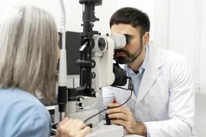 Ophthalmologist using slit lamp to examine patient's eyes in modern clinic photo