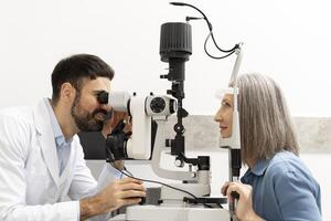 Ophthalmologist examining senior patient's eyes with slit lamp in clinic photo