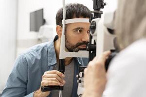 Optometrist examining patient's eyesight with slit lamp biomicroscope in ophthalmology clinic photo