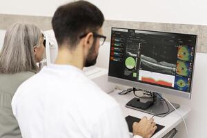 Ophthalmologist analyzing optical coherence tomography scan results on computer photo
