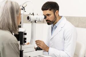 Ophthalmologist examining senior woman's eyesight with slit lamp biomicroscope in clinic photo