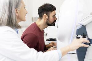 Optometrist performing eye exam on patient using phoropter photo