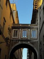 Exploring the historic architecture of a narrow street with a bridge connecting two buildings in a vibrant city under clear blue skies photo