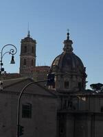 Historic architecture featuring a dome and bell tower against a clear blue sky in an urban setting during daylight photo