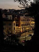 Evening view of a bustling street in a city illuminated by warm lights showcasing lively activity and charming architecture photo