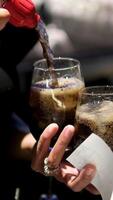 pour bottle of cola into a glass filled with ice cubes video