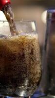 Pouring Cola with ice cubes close-up. Cola with Ice and bubbles in glass. Coke Soda closeup. Food background. Rotate glass of Cola fizzy drink over brown background. video
