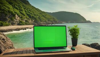 Laptop on a Table with a Green Screen in Front of the Ocean photo