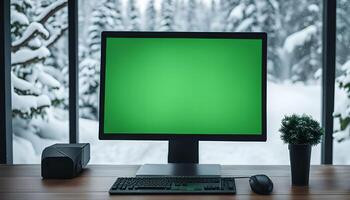 Computer on a Desk with a Snowy Winter Scene in the Background photo