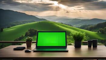 Laptop on a wooden desk with a green screen and a mountain range as background photo
