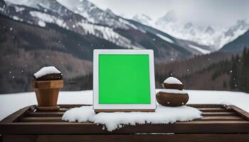 Tablet with Green Screen on Snowy Mountain Background photo