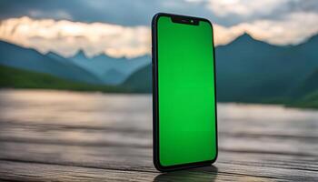 Smartphone with Green Screen in Front of Mountain Landscape photo
